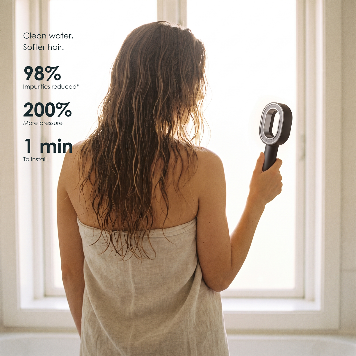 Woman holding the HAIRBLOOM filtering shower head by a window